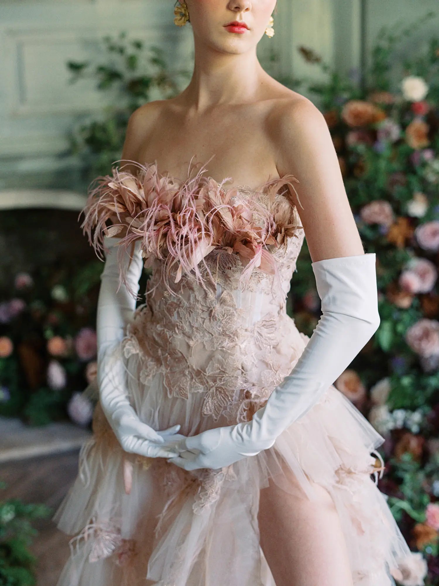 A woman in a pink dress with feathers and white gloves. She is wearing elegant over-the-elbow gloves, The Sunny - White Opera Gloves by LadyFinch, that perfectly complement her outfit, making her look even more stunning. These gloves are pure.