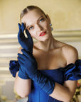 Women elegantly touching face wearing blue formal gloves.
