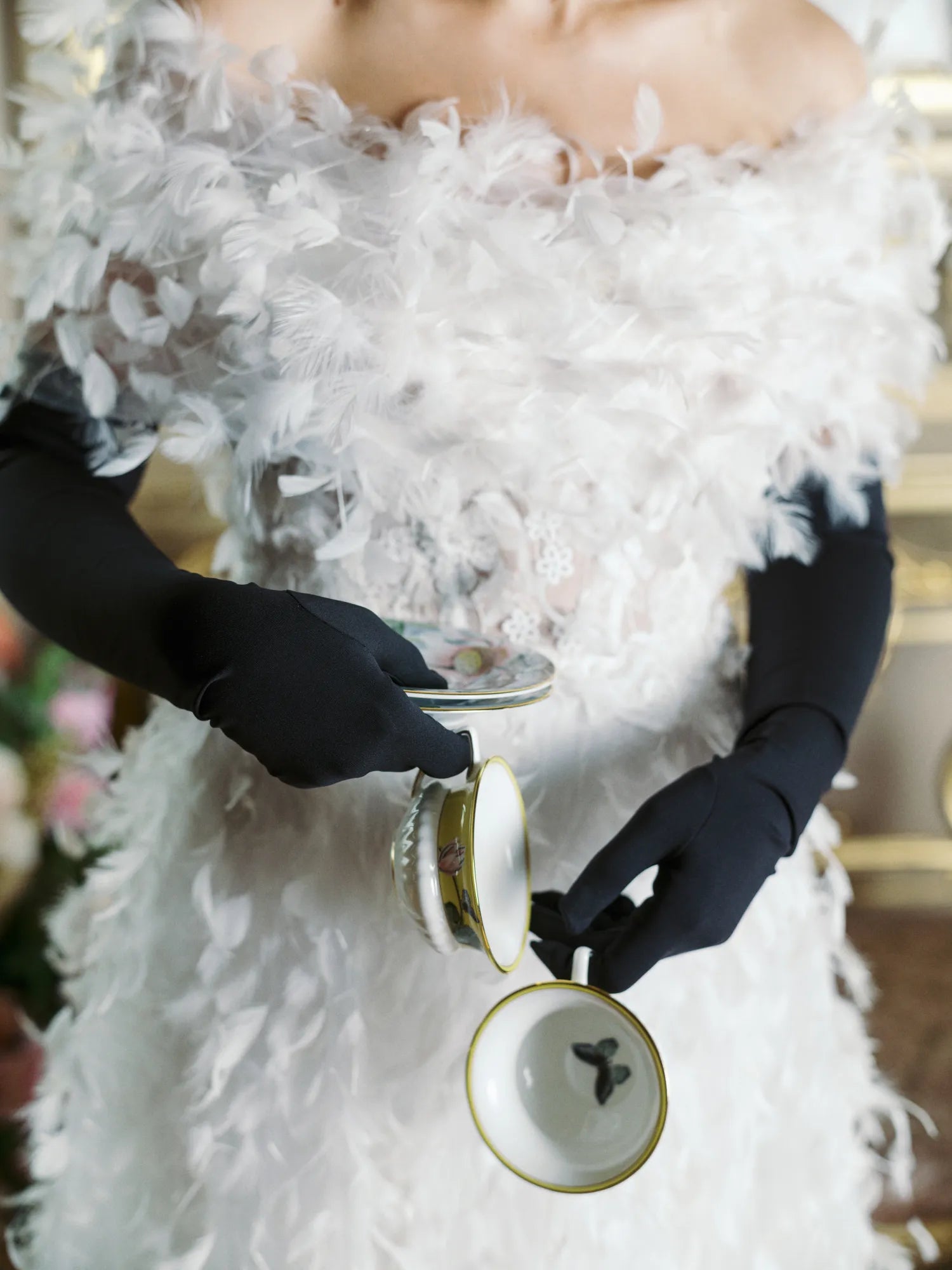 Woman wearing white feather dress wearing opera, long black gloves.