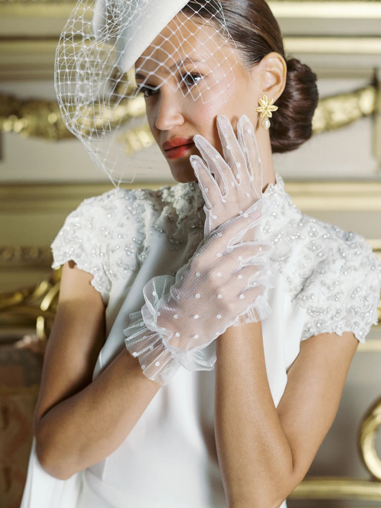 Bride touching her face wearing white tulle polka dot golves.