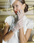 Bride touching her face wearing white tulle polka dot golves.