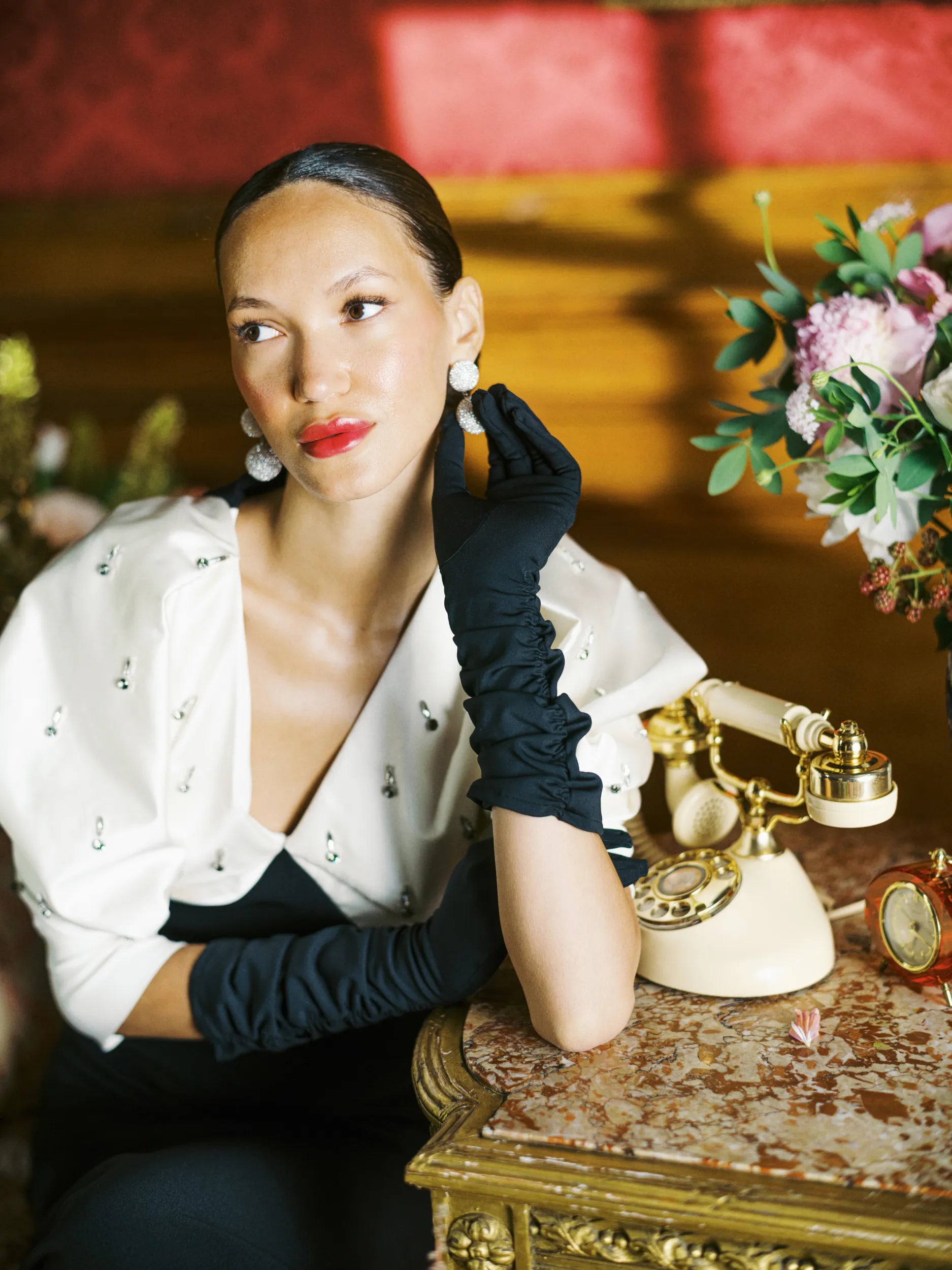 A woman in a black dress and THE STEPHANIE - Long Gloves Black by LadyFinch sitting on a table.