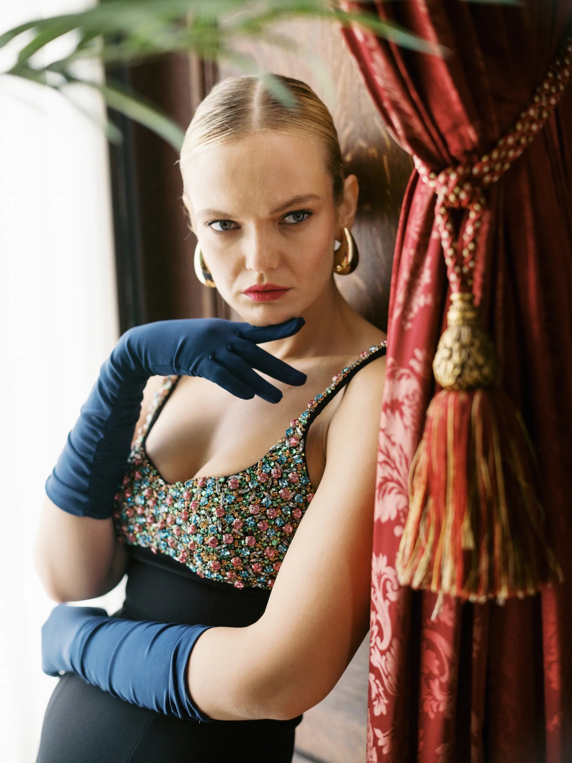 A woman standing, poised, wearing elbow length, dark blue gloves.