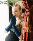 A beautiful woman in a black dress with THE STEPHANIE - Long Gloves Parisian Blue from LadyFinch, elevating any outfit to new heights of elegance.