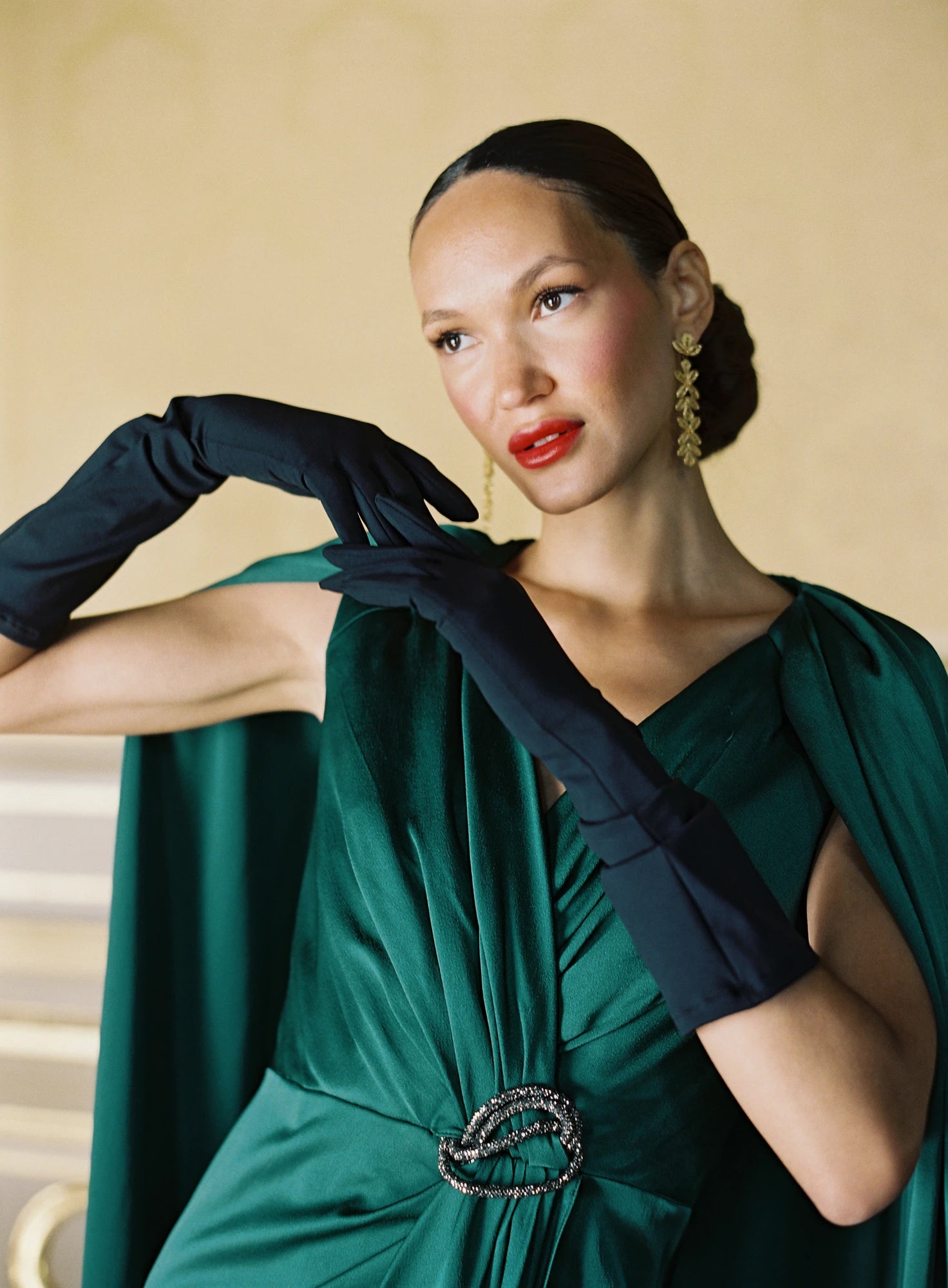 Woman wearing emerald green formal dress and long black gloves.