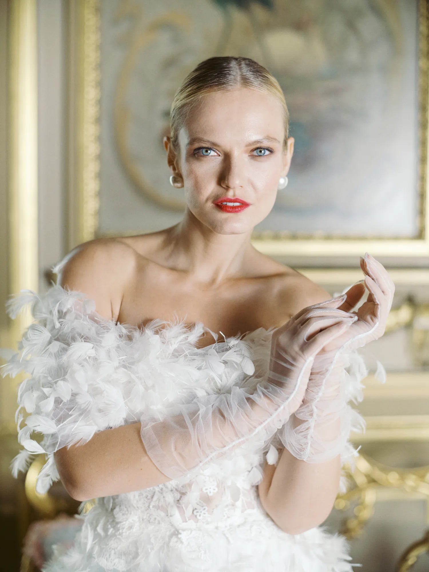 Bride in white feather dress wearing white tulle bridal wedding gloves.