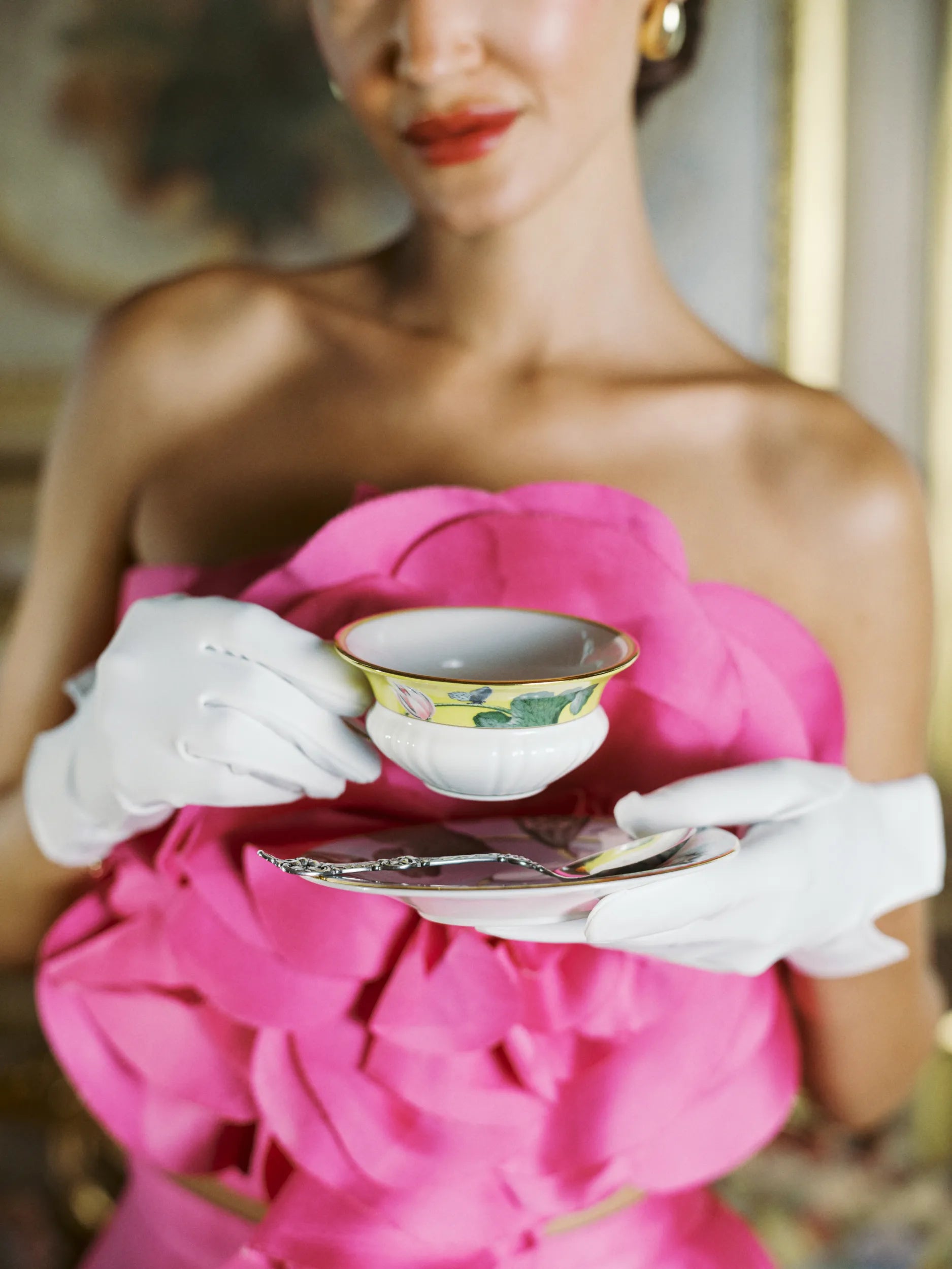 Woman holding tea cup with elegant white day gloves.
