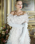Elegant woman in white feather dress with white opera gloves.