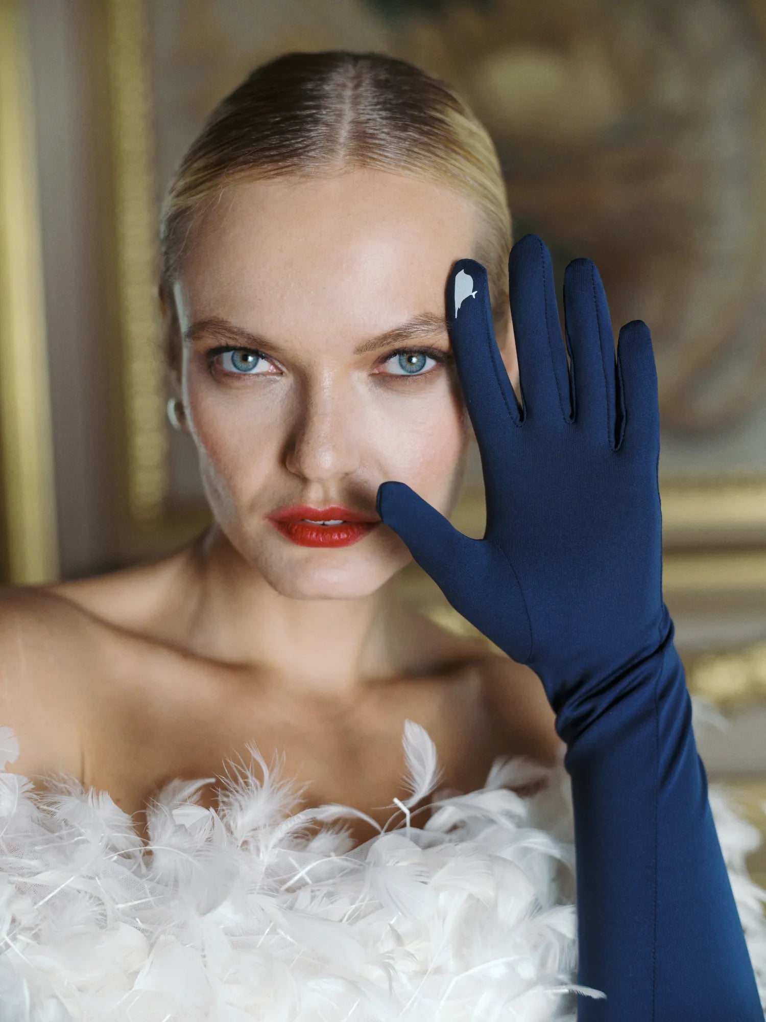 Glamorous woman wearing over the elbow blue opera gloves with palm open to show technology touchscreen index finger.