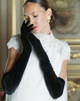 Elegant women wearing over the elbow black velvet gloves.