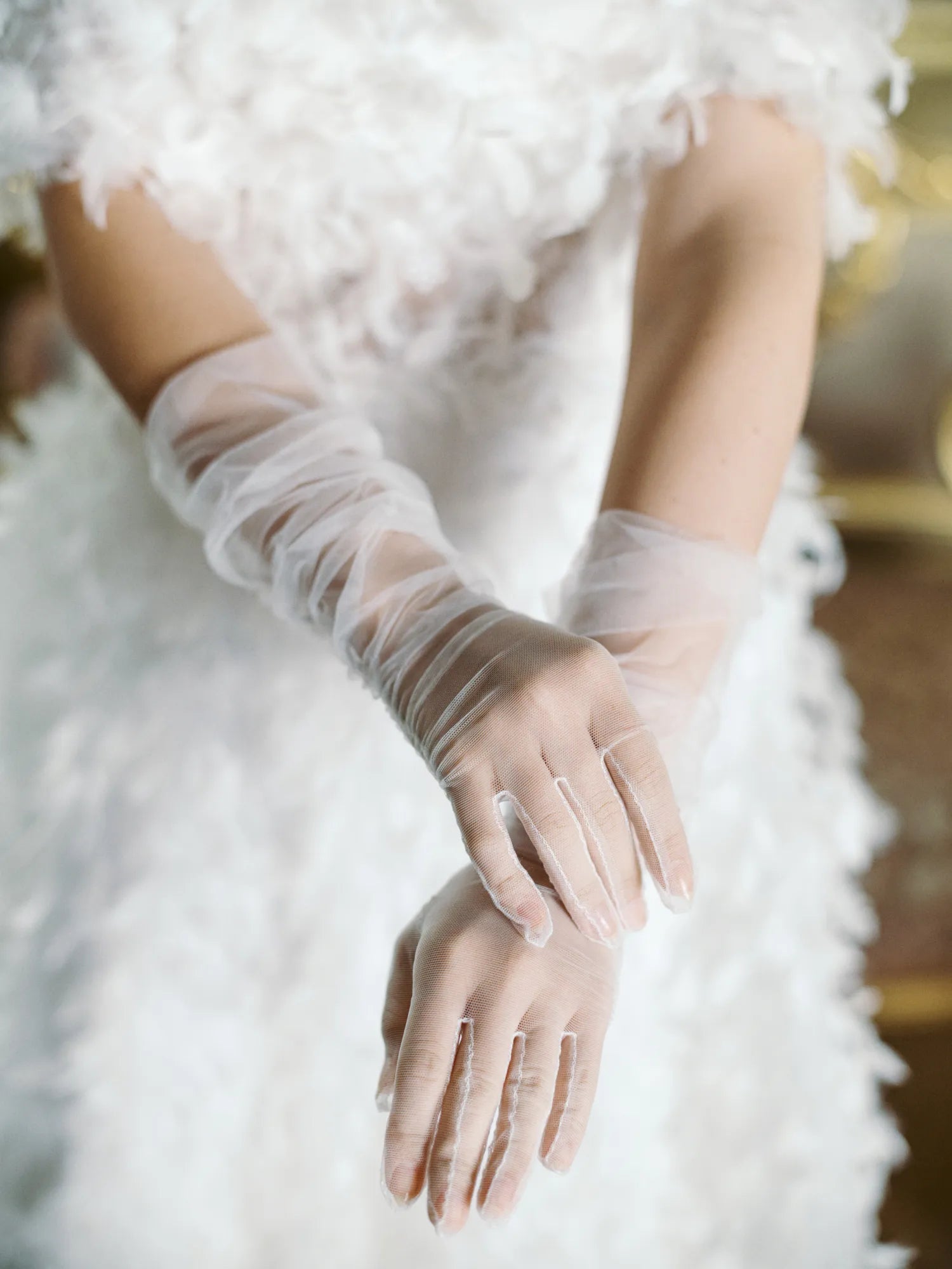 Woman in white dress, holding out hands wearing white fitted tulle gloves.